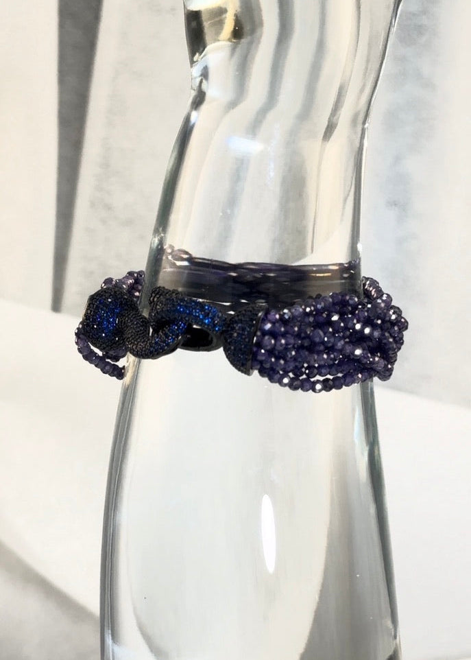 Dark blue crystal beads, blue clasp, clear glass display, white background