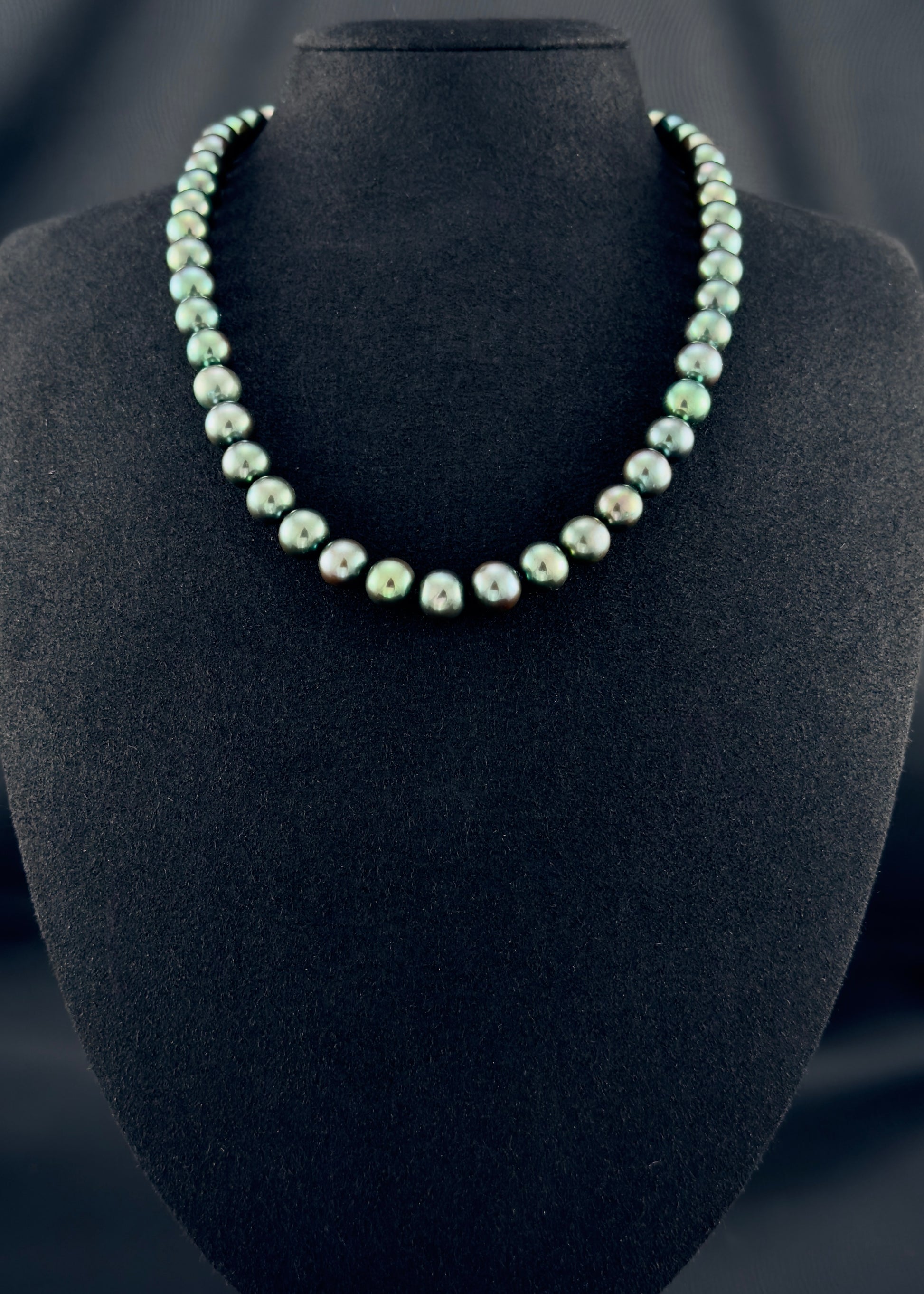 Cultured, Tahitian dark-pistachio pearl necklace, exhibited on black suede, excellent reflection, 9-10mm, 18", white gold clasp.
