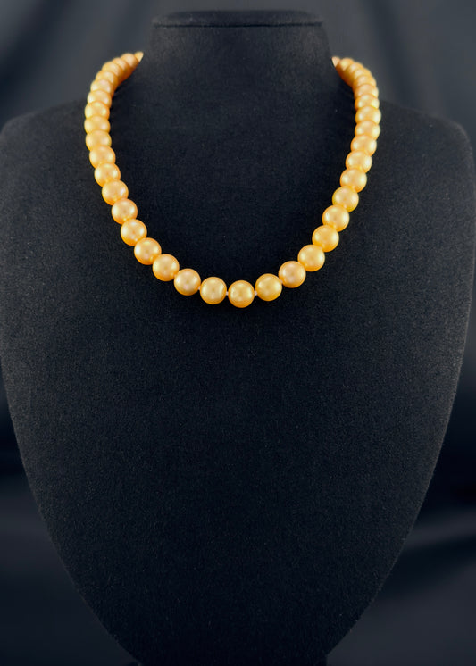 Cultured, South Sea deep-gold pearl necklace, exhibited on black suede, excellent reflection, 9-10mm, 18", yellow gold clasp.