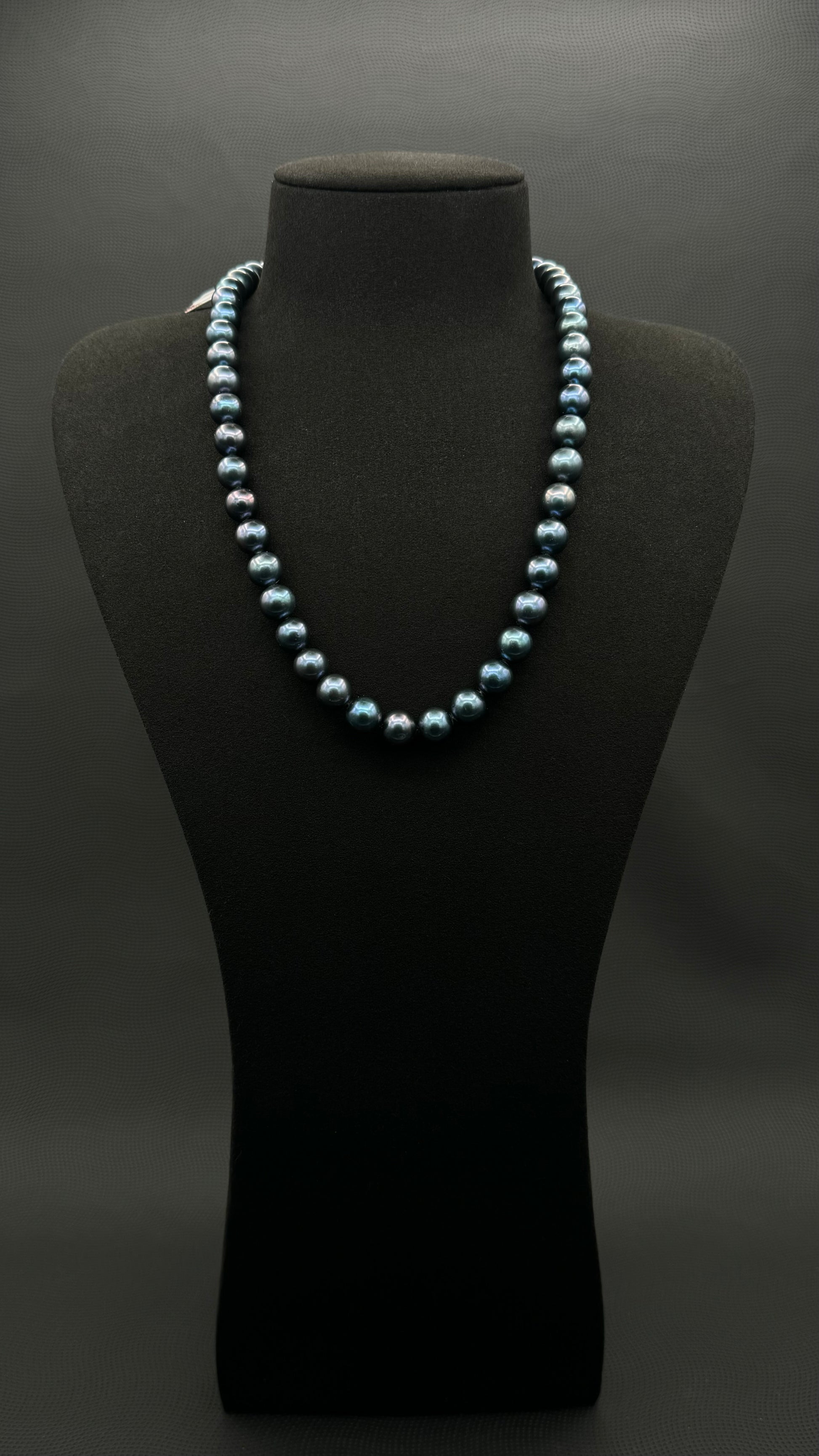 Cultured, South Sea dark-blue pearl strand necklace, exhibited on black suede, sound reflection, 9-10mm, 20", yellow gold clasp.