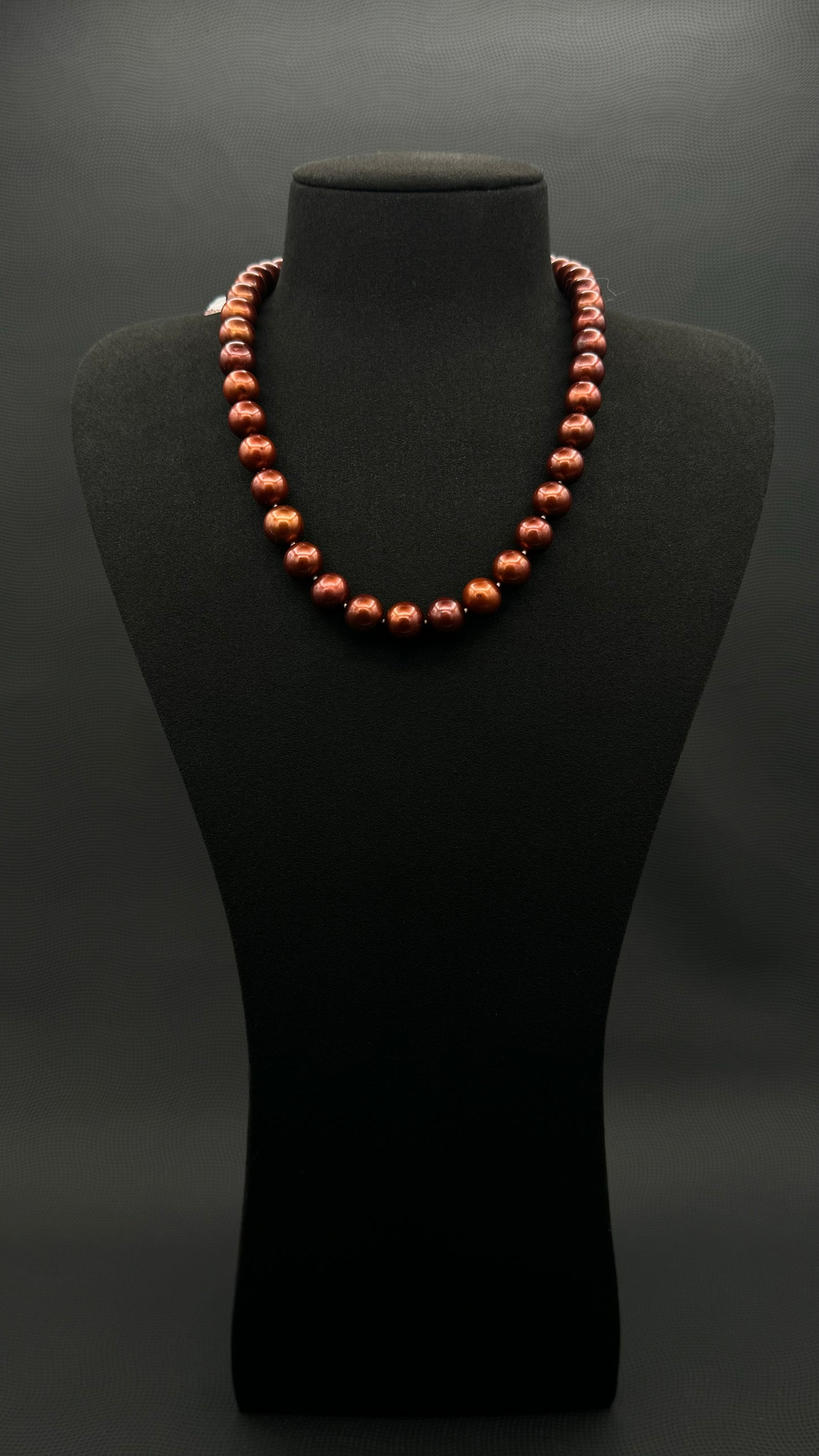 Cultured, Tahitian russet-brown pearl strand necklace, exhibited on black suede, excellent reflection, 10.5-11mm, 18", yellow gold clasp.