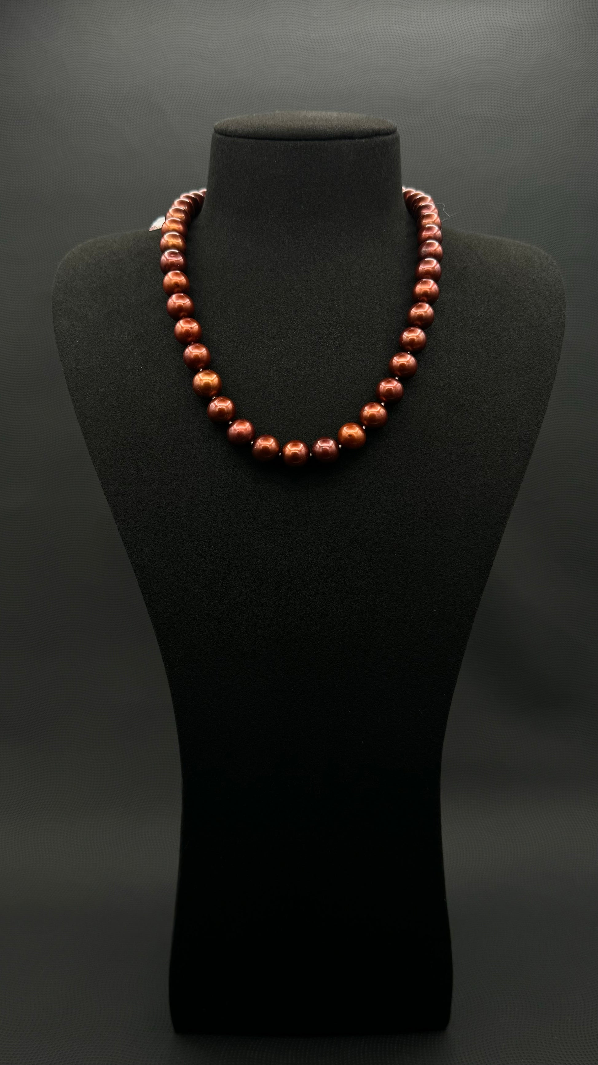 Cultured, Tahitian russet-brown pearl strand necklace, exhibited on black suede, excellent reflection, 10.5-11mm, 18", yellow gold clasp.