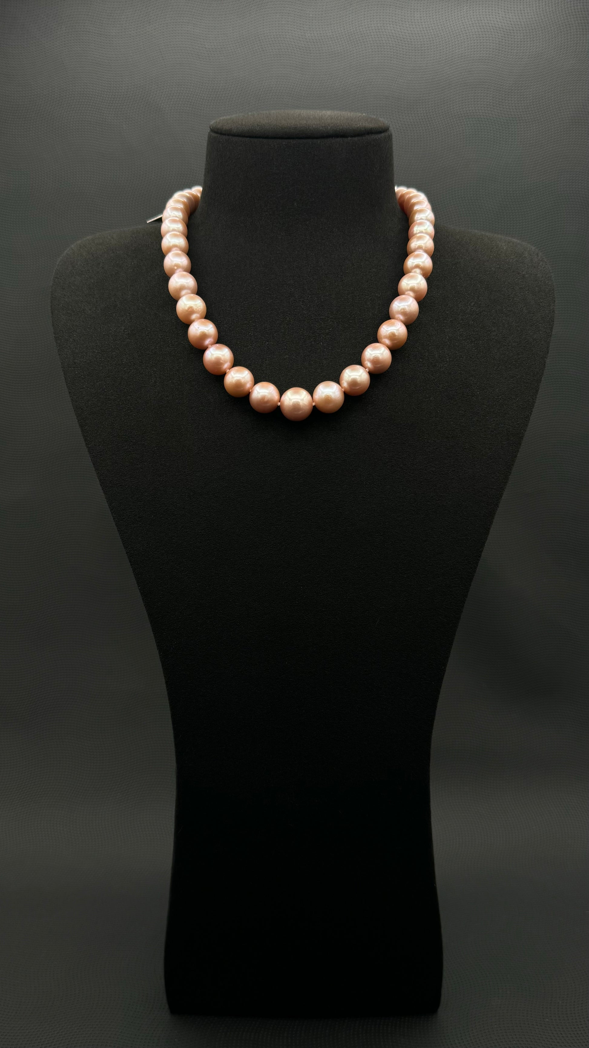 Cultured, South Sea pink pearl strand necklace, exhibited on black suede, excellent reflection, 10-12.5mm, 17.5", sterling silver clasp.