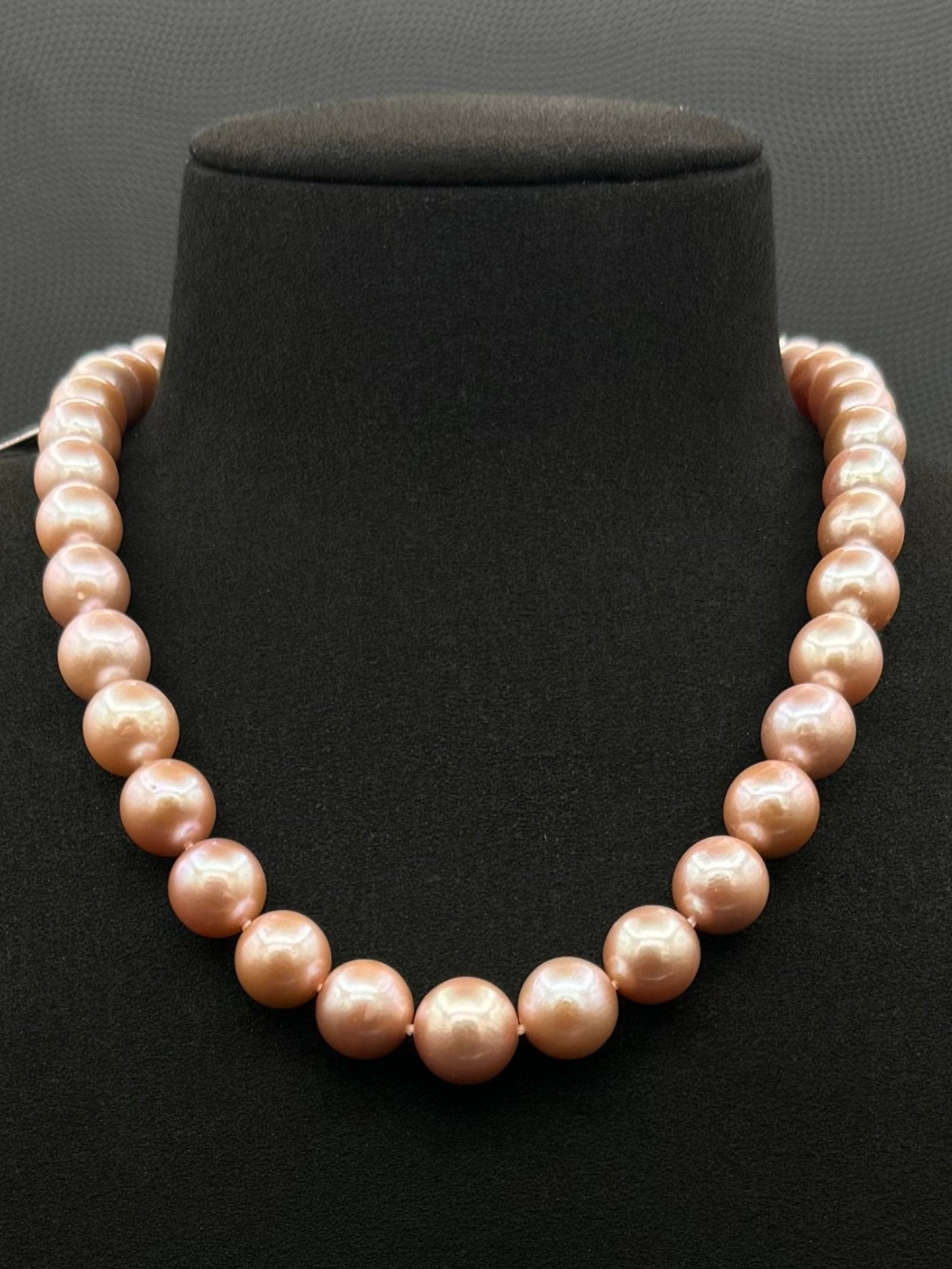 Cultured, South Sea pink pearl strand necklace, exhibited on black suede, excellent reflection, 10-12.5mm, 17.5", sterling silver clasp.