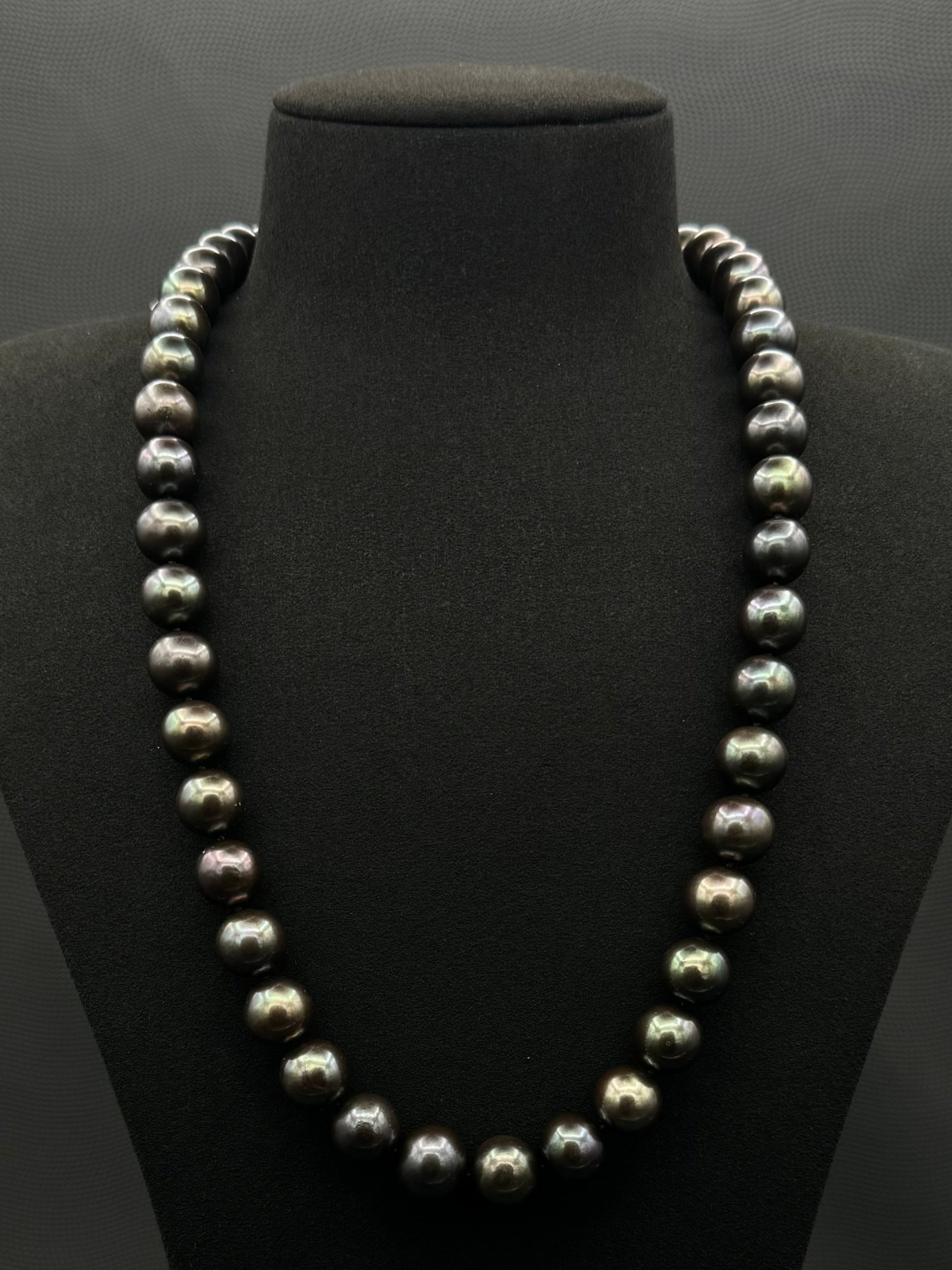 Cultured, Tahitian black-green continuous strand pearl necklace, exhibited on black suede, excellent reflection, 11.5-12.5mm, 24", no clasp.
