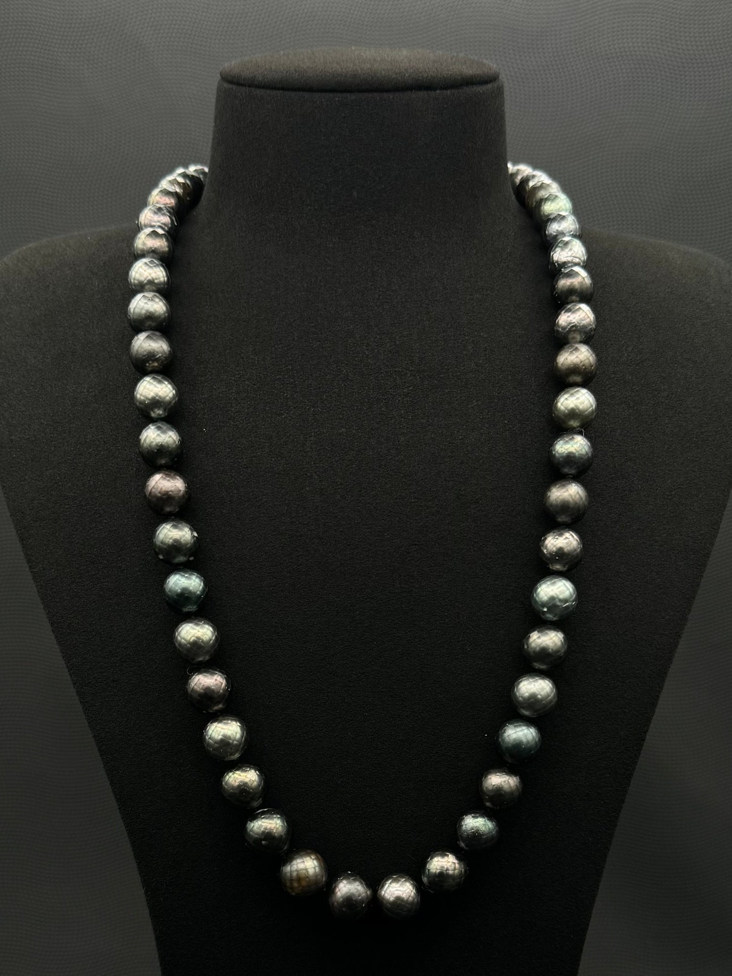 Cultured, Tahitian Carved black-green continuous strand pearl necklace, exhibited on black suede, fair to sound reflection, 10mm, 24", no clasp.