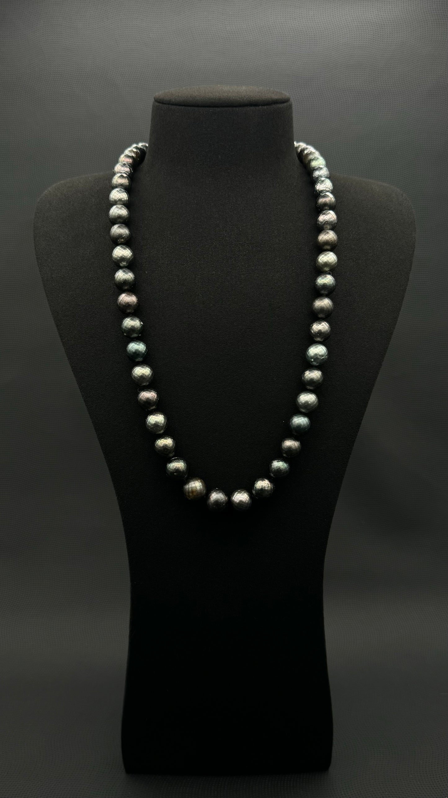 Cultured, Tahitian Carved black-green continuous strand pearl necklace, exhibited on black suede, fair to sound reflection, 10mm, 24", no clasp.