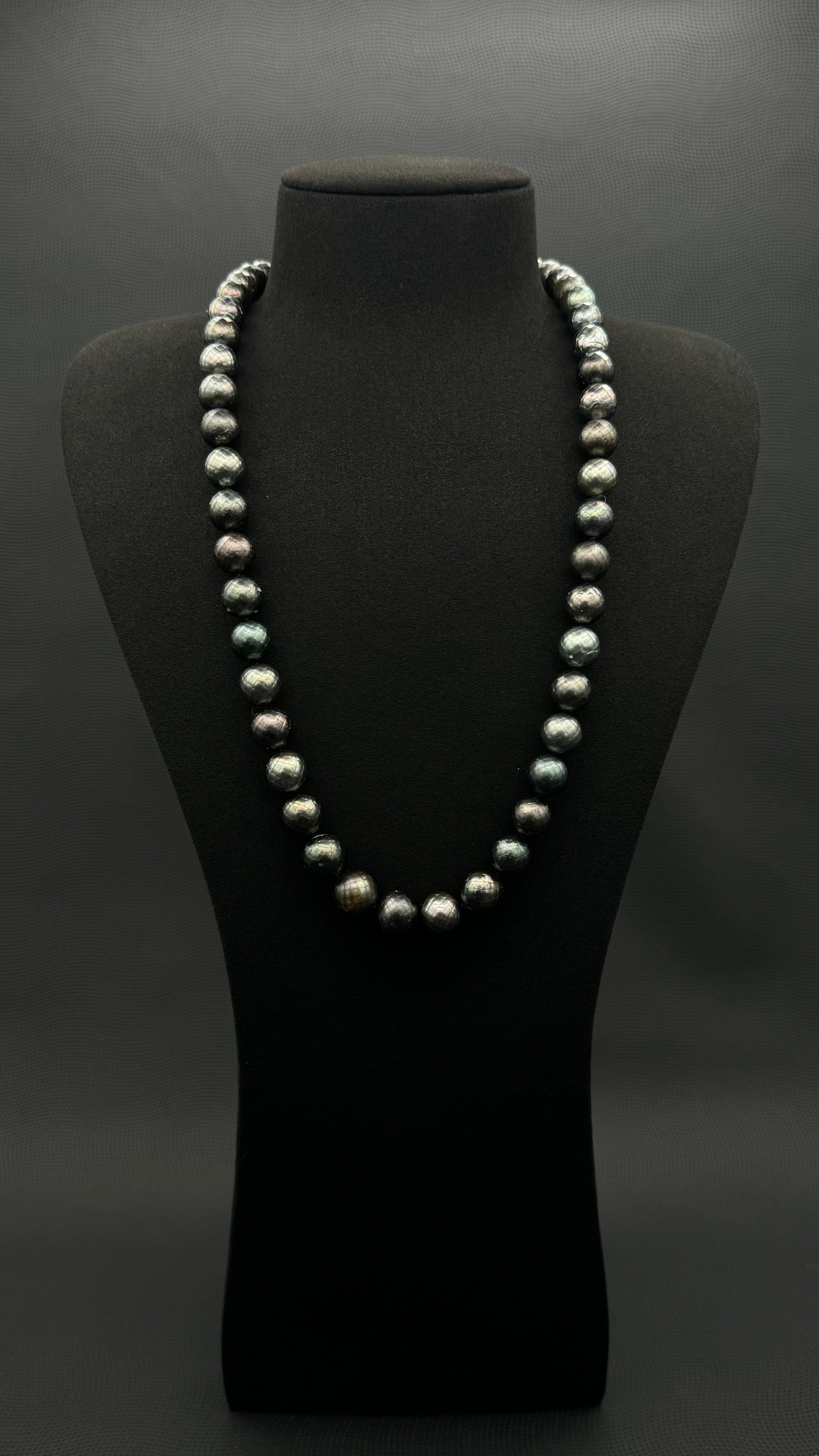 Cultured, Tahitian Carved black-green continuous strand pearl necklace, exhibited on black suede, fair to sound reflection, 10mm, 24", no clasp.