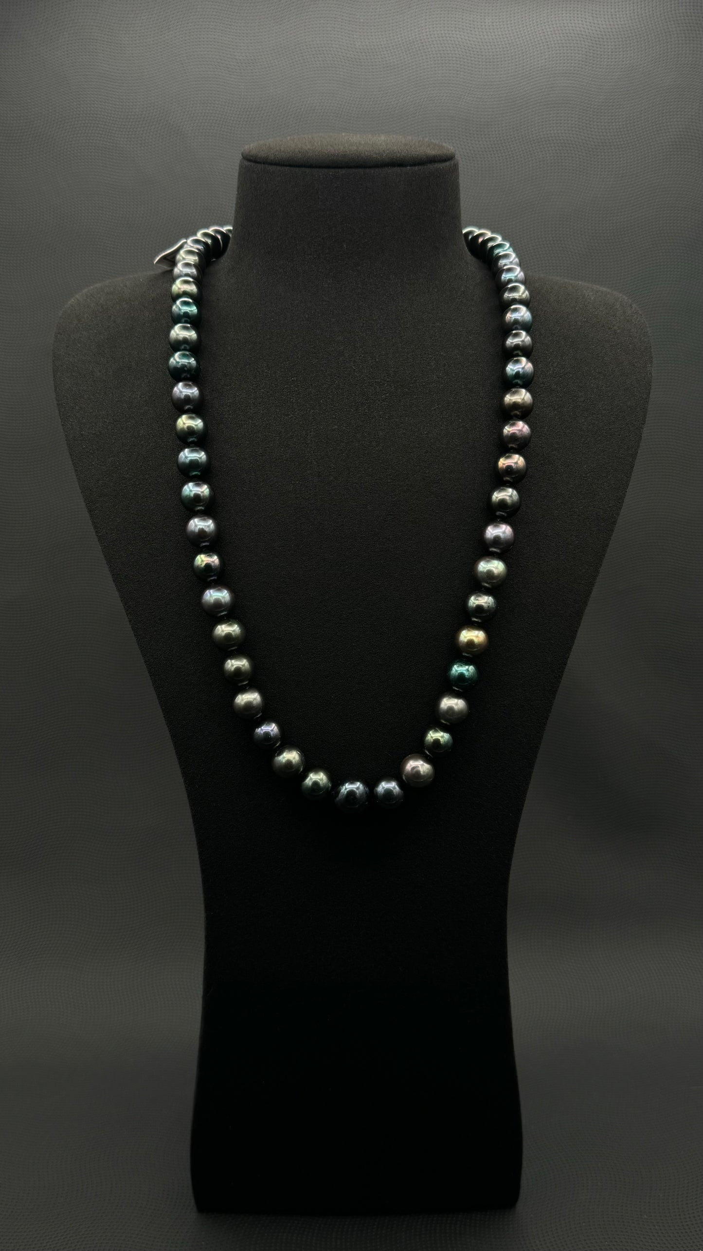 Cultured, Tahitian black-green pearl necklace, exhibited on black suede, excellent reflection, 10.5-13mm, 24", white gold clasp.