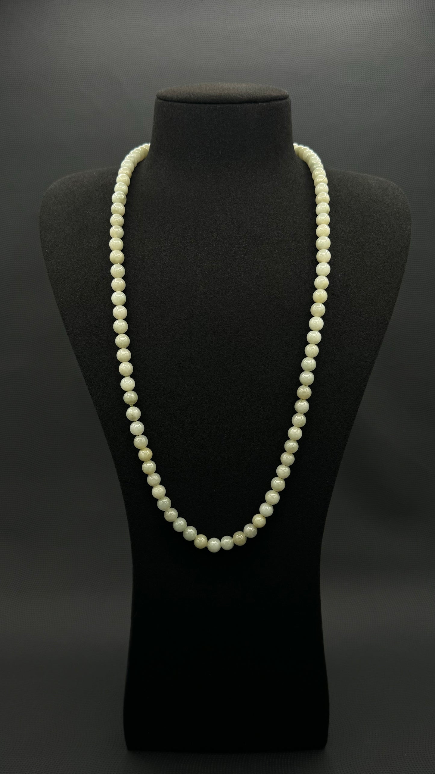 Genuine, Jade necklace, strand of continuous light green beads, exhibited on black suede, 7.5mm, 27"
