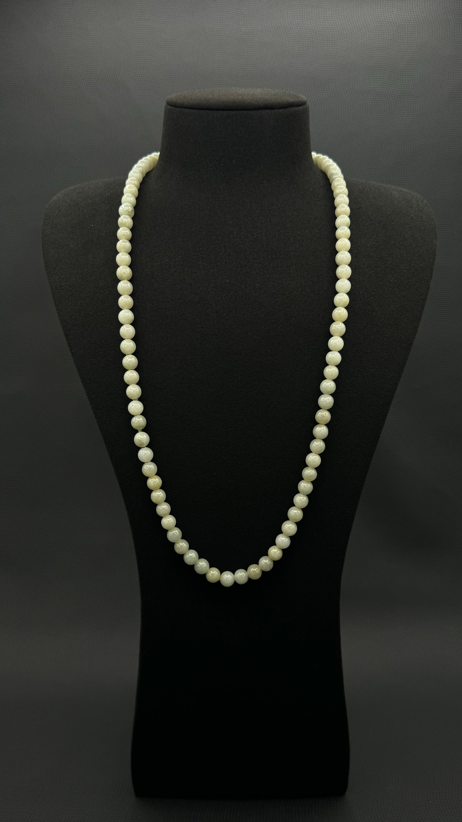Genuine, Jade necklace, strand of continuous light green beads, exhibited on black suede, 7.5mm, 27"