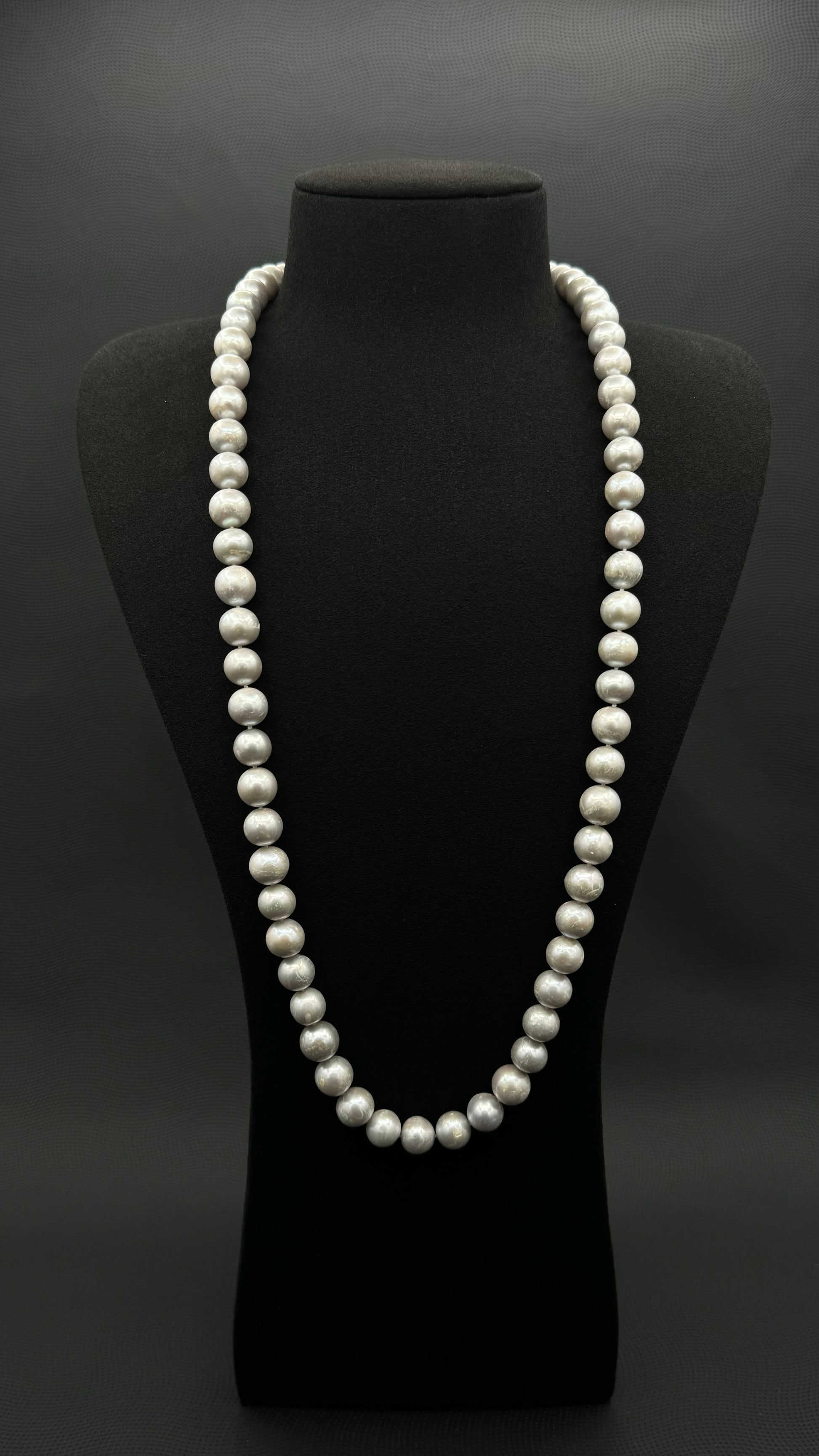 Cultured, South Sea, soft grey continuous strand pearl necklace, exhibited on black suede, fair reflection, 10-11mm, 30", no clasp.