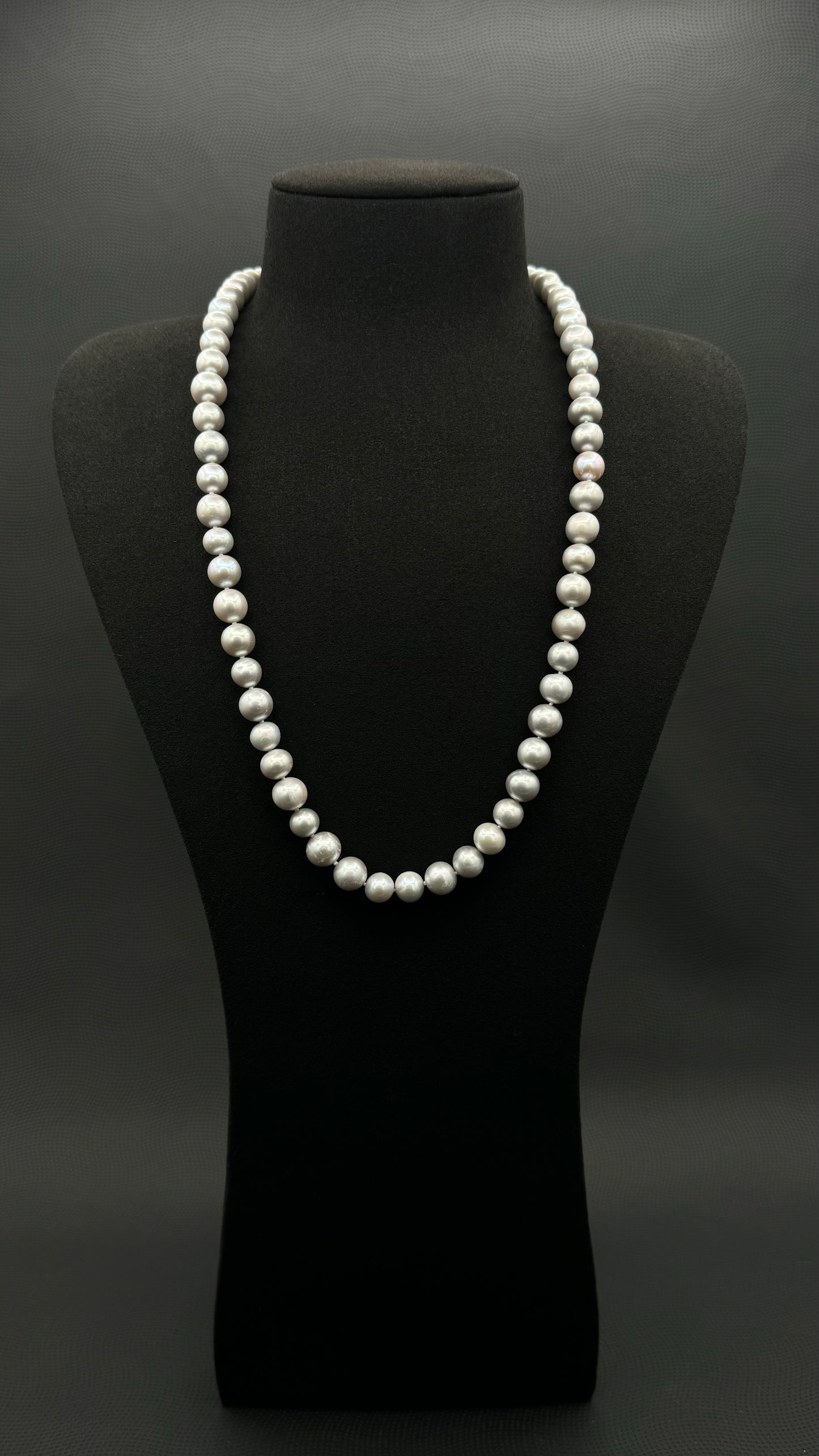 Cultured, South Sea soft grey pearl continuous strand necklace, exhibited on black suede, fair reflection, 9-10mm, 24", no clasp.