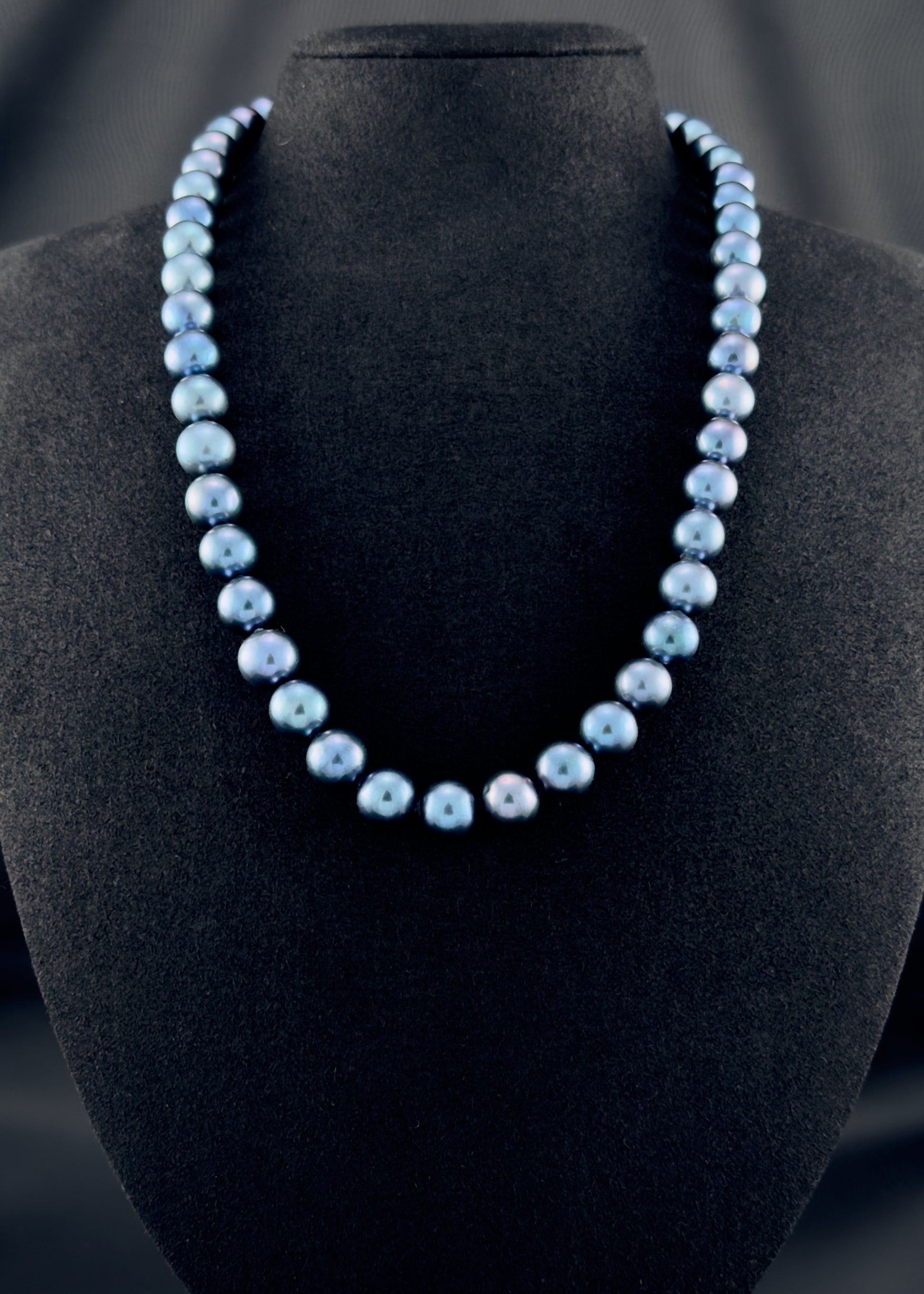 Cultured, South Sea dark-blue pearl strand necklace, exhibited on black suede, sound reflection, 9-10mm, 20", yellow gold clasp.