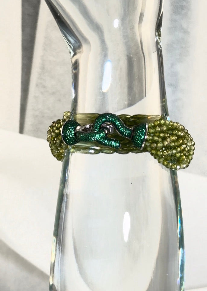 Green beaded bracelet on a clear glass display with a blurred background green crystal beads and green crystal clasp