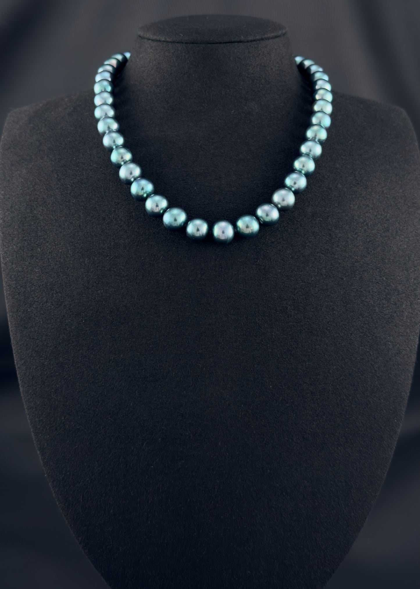 Cultured, Tahitian, green-blue pearl strand necklace, exhibited on black suede, sound reflection, 11-12mm, 16", yellow gold clasp.